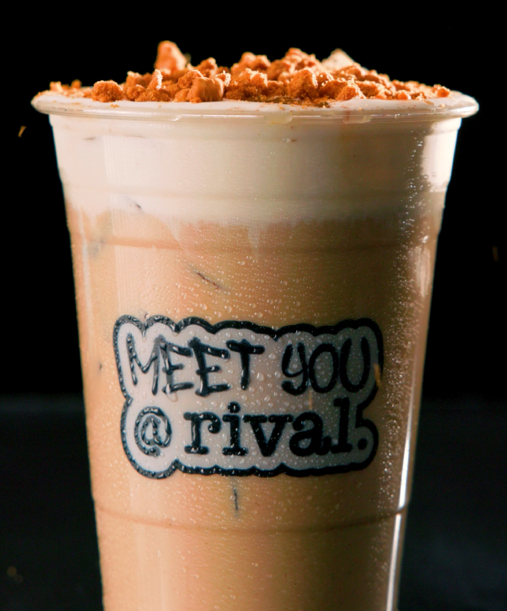 A white cup of coffee with latte art on top, sitting on a saucer on a wooden table.