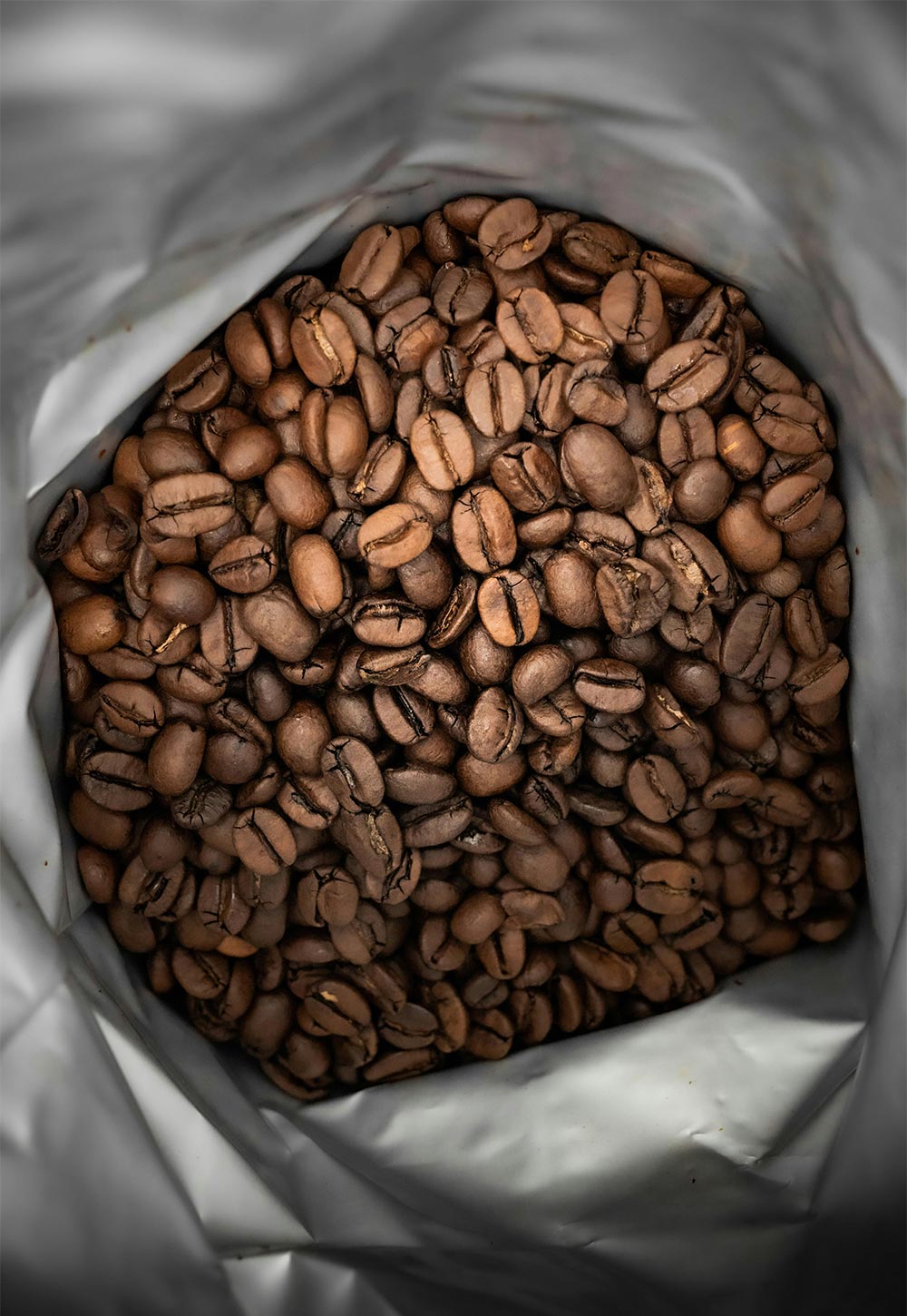 A close-up view inside a bag filled with roasted coffee beans.